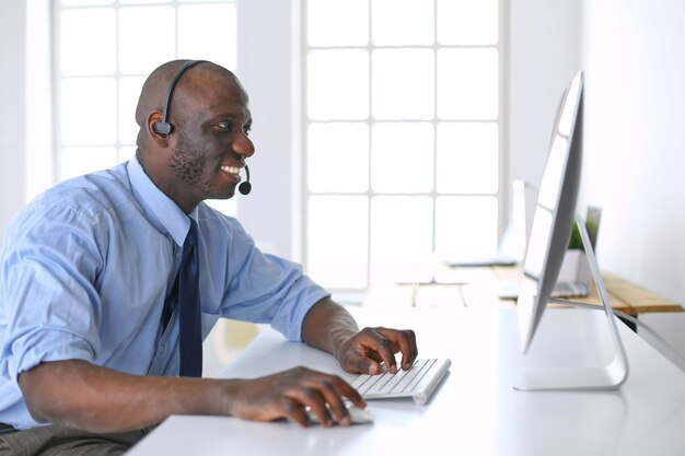 Empresário americano africano no fone de ouvido trabalhando em seu laptop