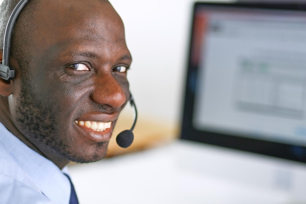 Empresário americano africano no fone de ouvido trabalhando em seu laptop