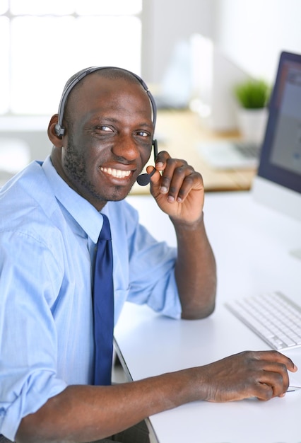 Empresário americano africano no fone de ouvido trabalhando em seu laptop