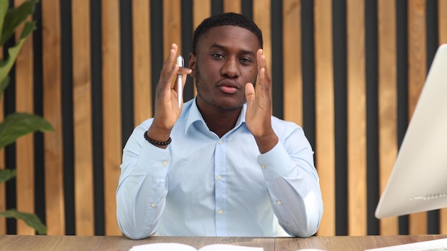 Empresário americano africano segurando a caneta e sentado na mesa do escritório