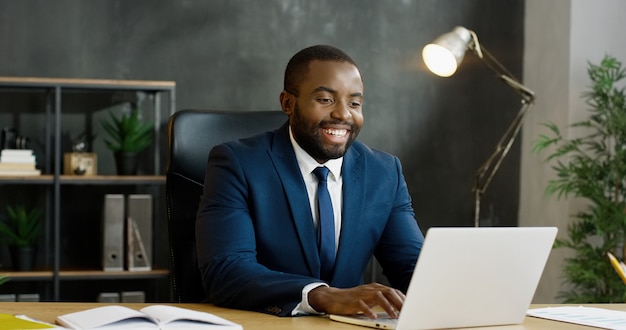 Empresário americano africano sentado à mesa e videochat no computador portátil.