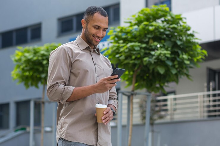Foto empresário americano africano sorrindo e feliz andando do lado de fora do prédio segurando uma xícara de