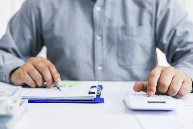 Foto empresário analisando gráficos de investimento e pressionando botões de calculadora sobre documentos conceito de contabilidade