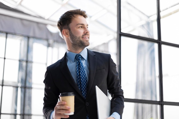 Empresário andando no corredor do escritório com café para viagem