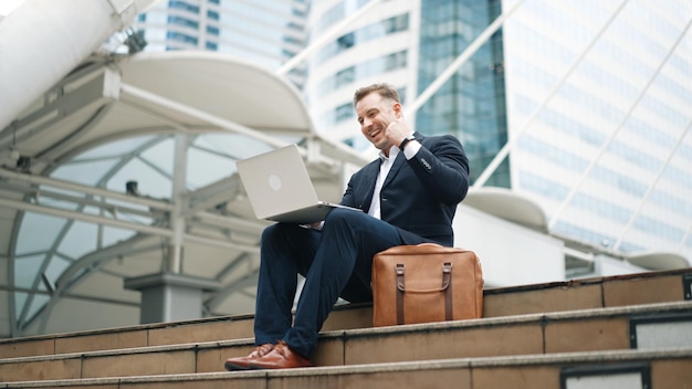 Empresario de bajo ángulo trabajando en una computadora portátil mientras celebra el exitoso Urbane