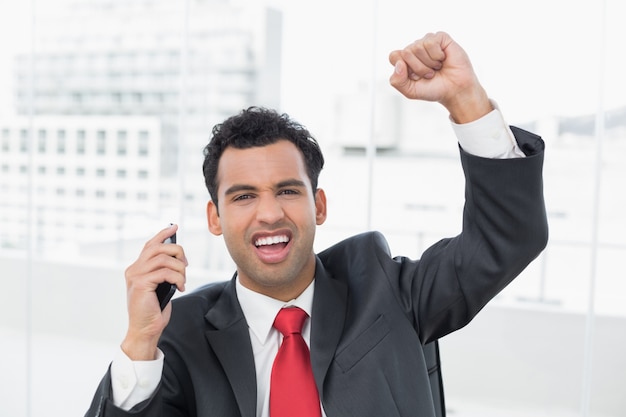 Empresario animando con el puño cerrado en la oficina