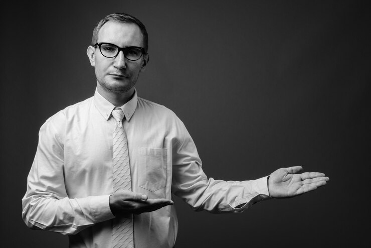 Foto empresario con anteojos contra la pared gris en blanco y negro