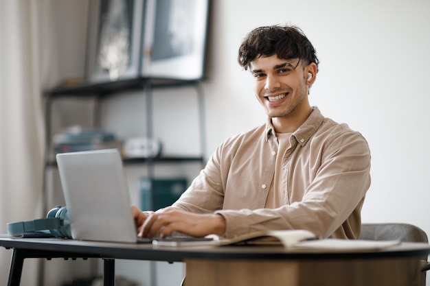 Foto empresario árabe sonriente que trabaja con una computadora portátil en el interior de su casa