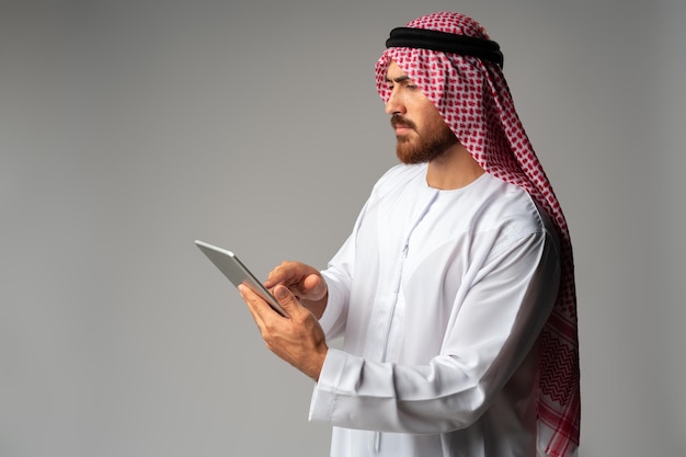Empresario árabe mediante tableta digital sobre fondo gris