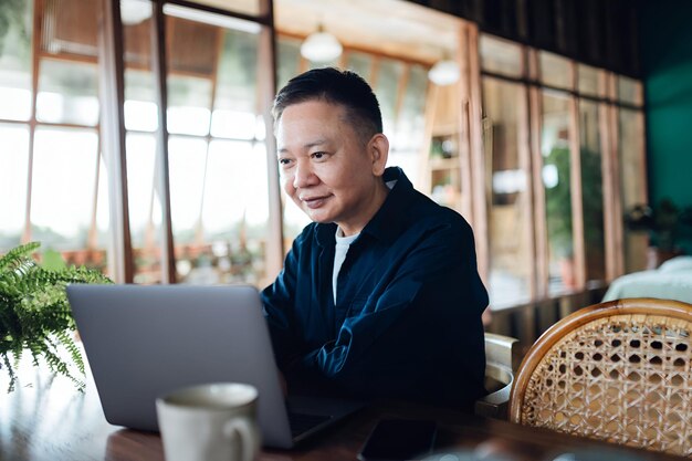 Foto empresario asiático de alto rango videoconferencia con sus socios de negocios en la computadora portátil en casa trabajar desde casa trabajo remoto ancianos y tecnología