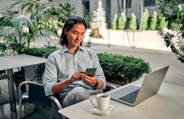 Empresario asiático en la ciudad. Joven confiado trabajando en un café.