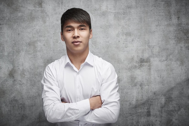 Empresário asiático em camisa sobre fundo cinza. retrato de um sorridente empresário bem-sucedido do cazaquistão com os braços cruzados