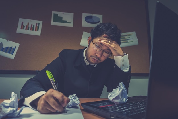 Empresario asiático bajo estrés debido al exceso de trabajoSentirse exhaustoEl empleado joven tiene un problema en una oficinaHombre triste del trabajoConcepto de hombre desordenado enojado