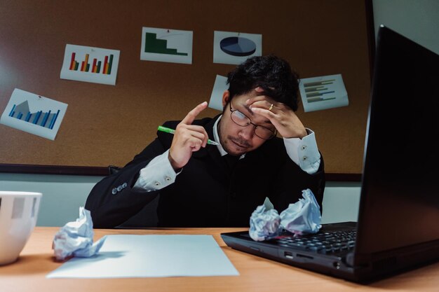 Empresario asiático bajo estrés debido al exceso de trabajoSentirse exhaustoEl empleado joven tiene un problema en una oficinaHombre triste del trabajoConcepto de hombre desordenado enojado
