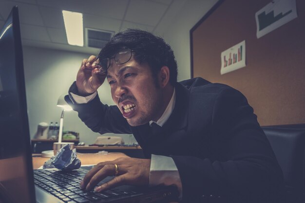 Empresario asiático bajo estrés debido al exceso de trabajoSentirse exhaustoEl empleado joven tiene un problema en una oficinaHombre triste del trabajoConcepto de hombre desordenado enojado