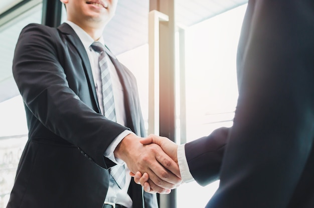 Empresário asiático fazendo handshake com uma empresária - conceitos de saudação e negociação