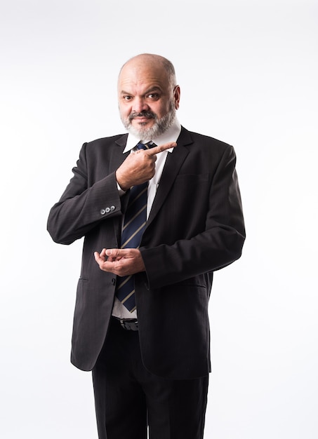 Empresario asiático indio de mediana edad con barba vistiendo elegante traje negro y apuntando con la mano y el dedo. presentando producto, servicio o espacio de copia