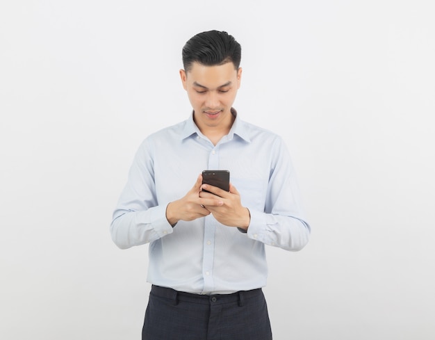 Empresario asiático jugando smartphone con una sonrisa aislado sobre fondo blanco.