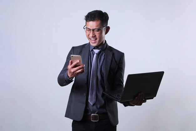 Un empresario asiático mirando smartphone con expresión feliz