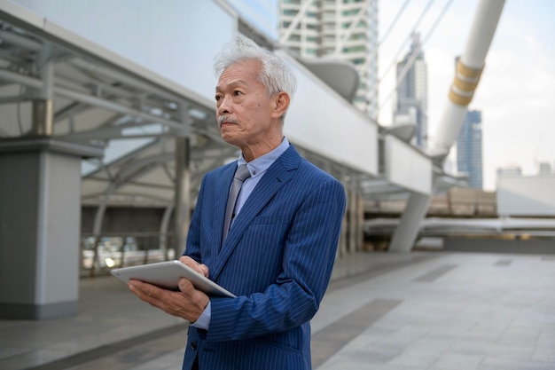 Empresário asiático sênior de meia-idade maduro usando tablet na cidade moderna