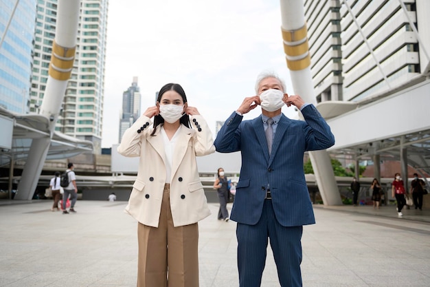 Empresario asiático senior maduro de mediana edad y joven empresaria quitándose la máscara en la ciudad moderna