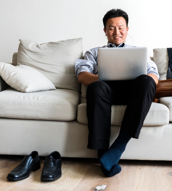 Empresario asiático tomando descanso tendido en el sofá