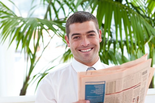 Empresario atractivo leyendo un periódico en el lugar de trabajo