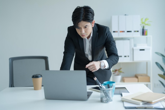 Empresário atraente trabalhando no laptop no escritório da estação de trabalho