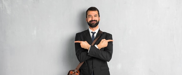 Empresario con barba apuntando a los laterales teniendo dudas.