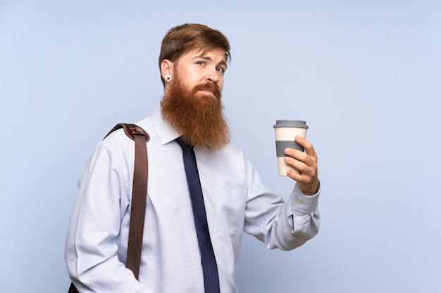 Empresario con barba larga con café para llevar sobre pared aislada