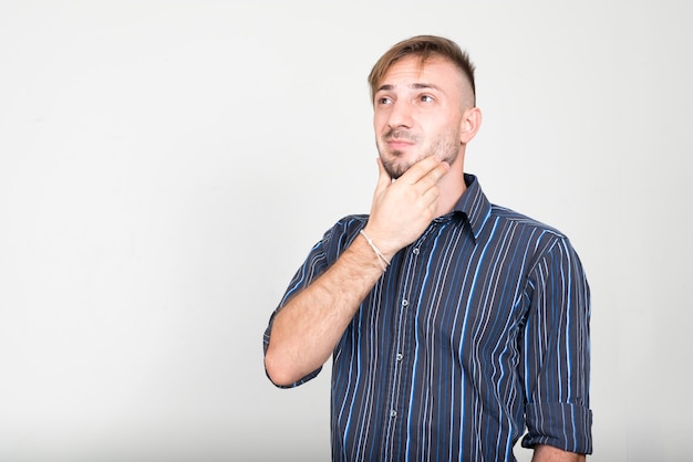 Empresario barbudo con cabello rubio contra la pared blanca