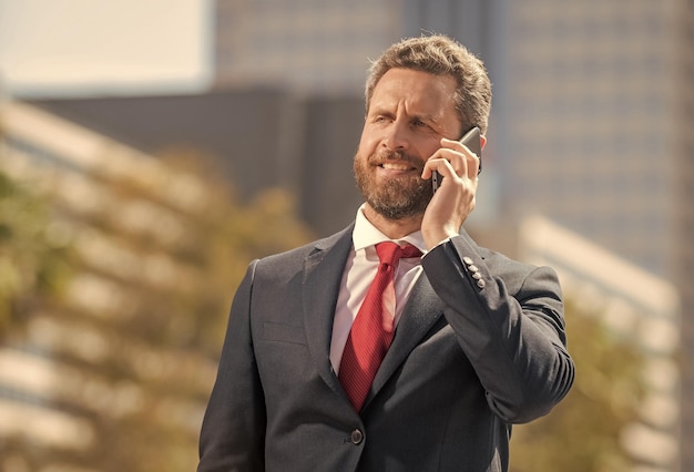 Empresário barbudo em trajes formais tem conversa telefônica fora da tecnologia móvel do escritório