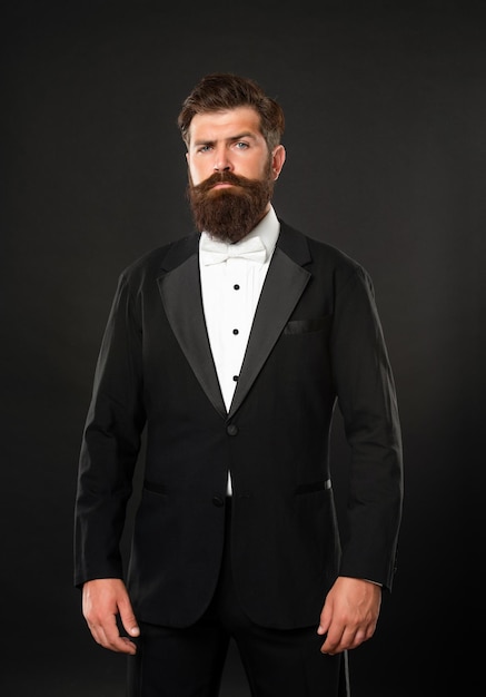 Empresario barbudo en esmoquin sobre fondo negro tux
