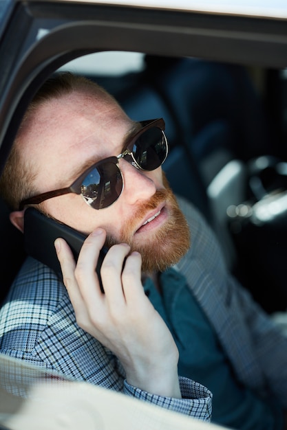Empresario barbudo hablando por teléfono dentro del coche