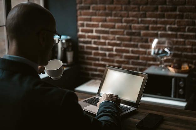 Empresário bebe café trabalhando com computador no centro de negócios. retrovisor de um homem branco