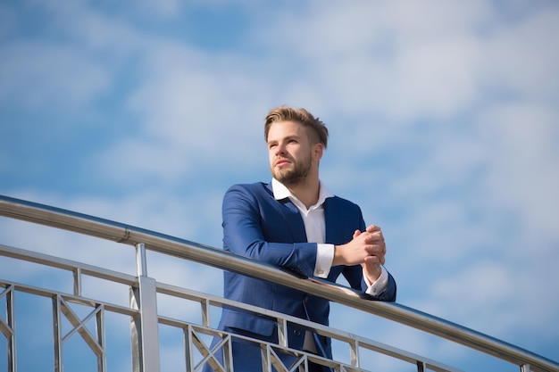 Empresário bem sucedido empresário de terno caminha fundo de céu de dia ensolarado ao ar livre Empresário aparência atraente parece bem sucedido Conceito de liberdade Homem confiante e bem preparado desfrutar de liberdade