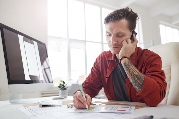 Empresário bem sucedido, falando por telefone no escritório