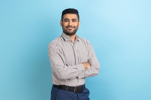 Empresário bem sucedido posando com expressão confiante feliz olhando para a câmera mantendo os braços cruzados