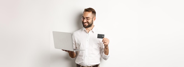 Empresário bonito de compras on-line segurando cartão de crédito e usando laptop fazendo pagamento pela internet st