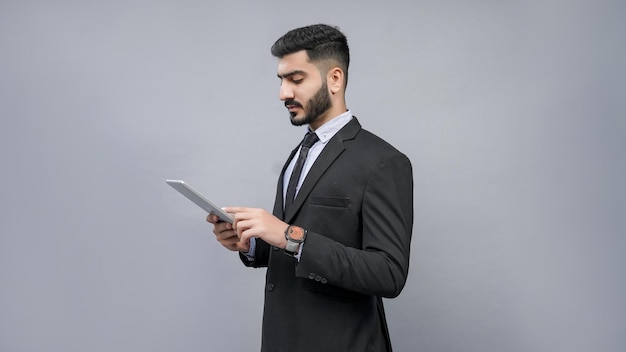 El empresario busca en la pestaña con pose del lado izquierdo en traje negro modelo paquistaní indio