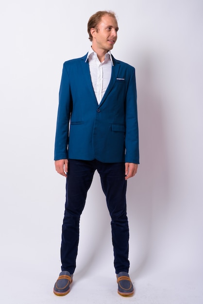 Foto empresario con cabello rubio vistiendo traje azul contra la pared blanca