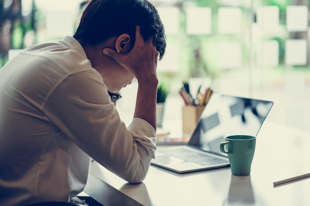 Foto empresario con la cabeza en las manos sentado en el escritorio