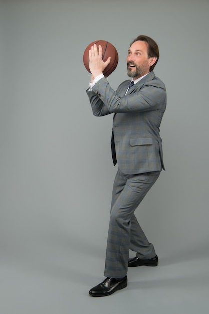 El empresario se calienta con el baloncesto en la oficina, se prepara para lanzar el concepto.