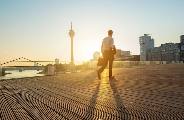 Empresario caminando sobre un puente al amanecer en dusseldorf