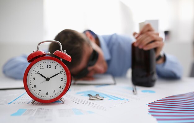 Empresario con camisa azul durmiendo en el trabajo en el fondo de una botella de alcohol se quedó dormido porque tormentosa noche de fiesta con una bebida después de la empresa el 1 de enero celebró el año nuevo muy mala resaca