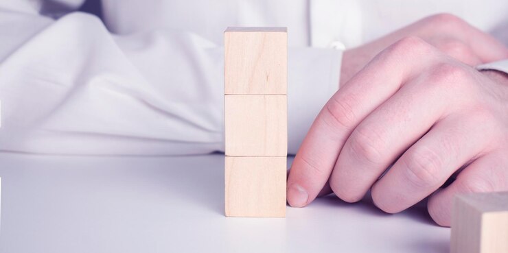 Empresario con una camisa azul que arregla los bloques de madera vacíos con las manos Que se coloca sobre una mesa de madera blanca Estrategia empresarial y plan de acción Copiar espacio
