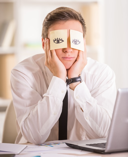 Empresário cansado com nota adesiva em seus olhos.