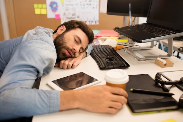 Foto empresario cansado tomando una siesta en el escritorio en la oficina creativa