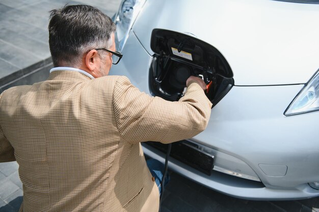 Un empresario carga un coche eléctrico.