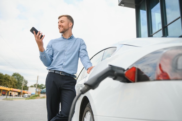 Un empresario carga un coche eléctrico.